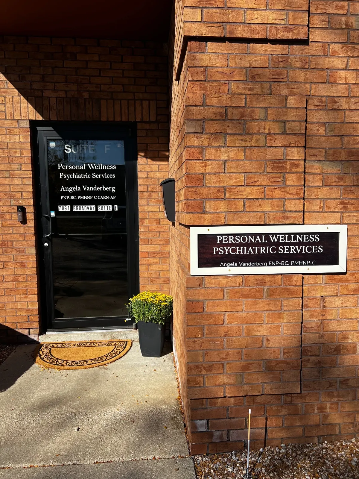 The south-facing Suite F door at 7891 Broadway in Merrillville, with the practice name on the glass and the Personal Wellness sign on the brick beside it