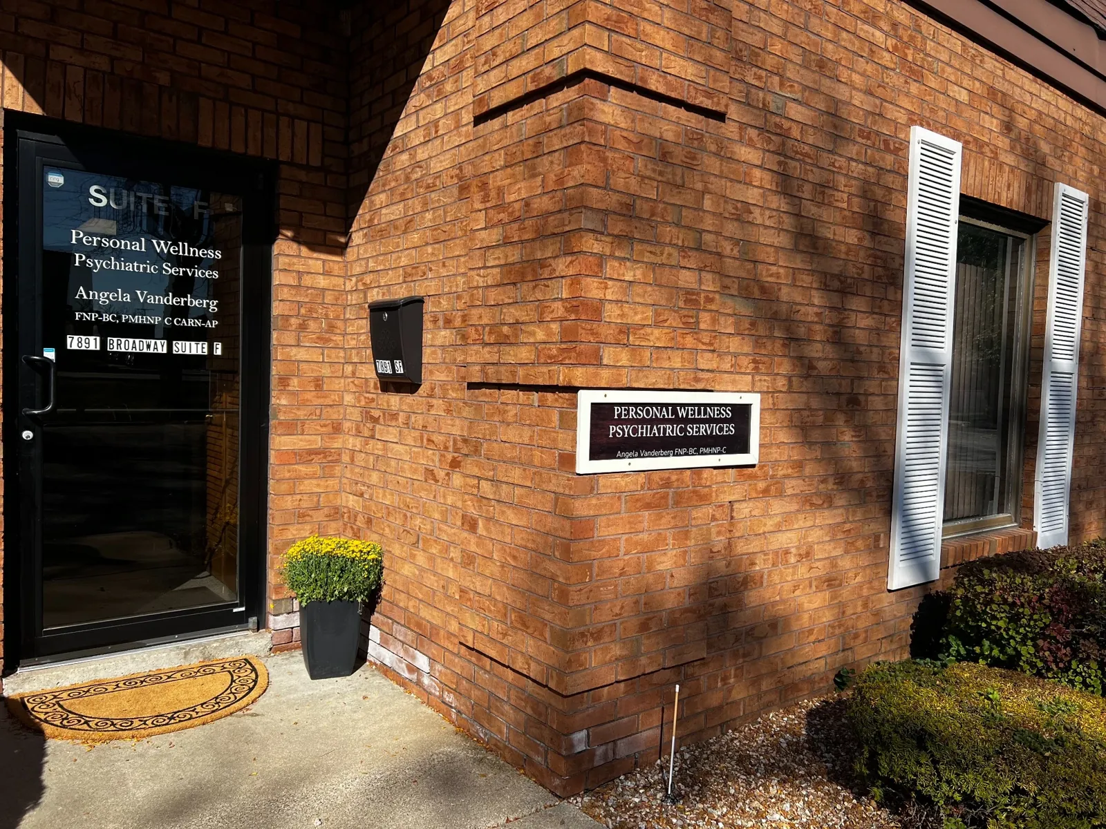 The Suite F entrance corner: the door and the Personal Wellness sign on the brick wall